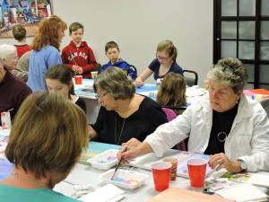 artist teaching painting class to mixed ages